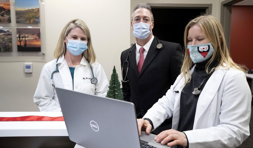 Molly Pruitt, left, a nurse practitioner, Dr. Mark Donnelly, center, and Dr. Tonya Cramer pose by a nurses station during the opening of a free health clinic for Station Casinos employees and their families at Red Rock Resort in Las Vegas, Tuesday, Dec. 15, 2020. The clinic is operated by Activate Healthcare. (Steve Marcus/Las Vegas Sun via AP)