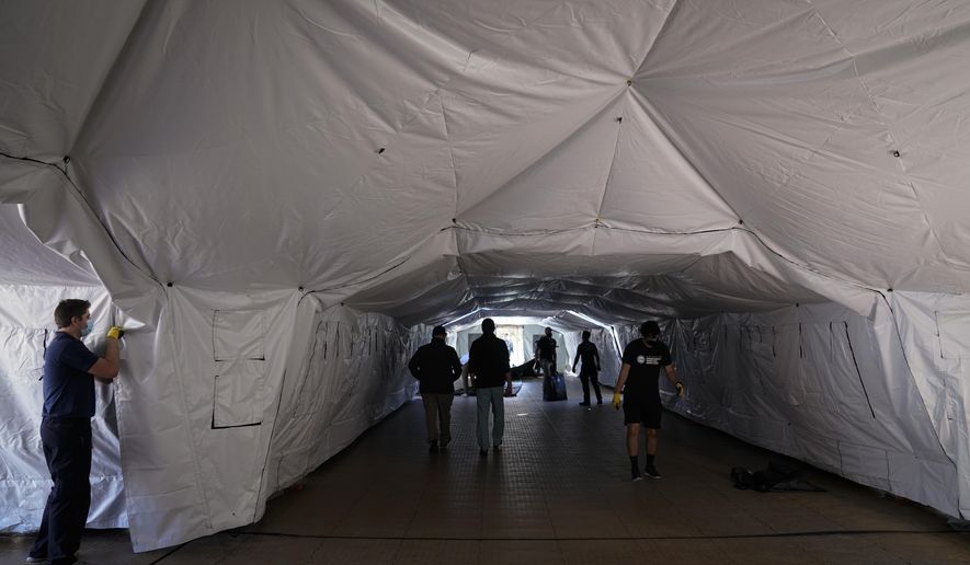 Engineers and volunteers help build a mobile field hospital at UCI Medical Center, Monday, Dec. 21, 2020, in Orange, Calif. California&#39;s overwhelmed hospitals are setting up makeshift extra beds for coronavirus patients, and a handful of facilities in hard-hit Los Angeles County are drawing up emergency plans in case they have to limit how many people receive life-saving care. (AP Photo/Jae C. Hong)
