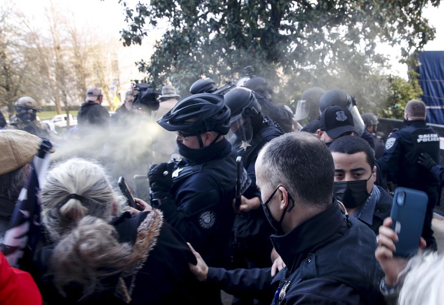 Protesters spray mace toward police as they attempt to get into the Oregon State Capitol during a special session of the state legislature in Salem, Ore., on Monday, Dec. 21, 2020. State police declared an unlawful assembly at Oregon’s Capitol building as protesters opposed to COVID-19 restrictions attempted to force their way in during the third special legislative session. (Abigail Dollins/Statesman-Journal via AP)