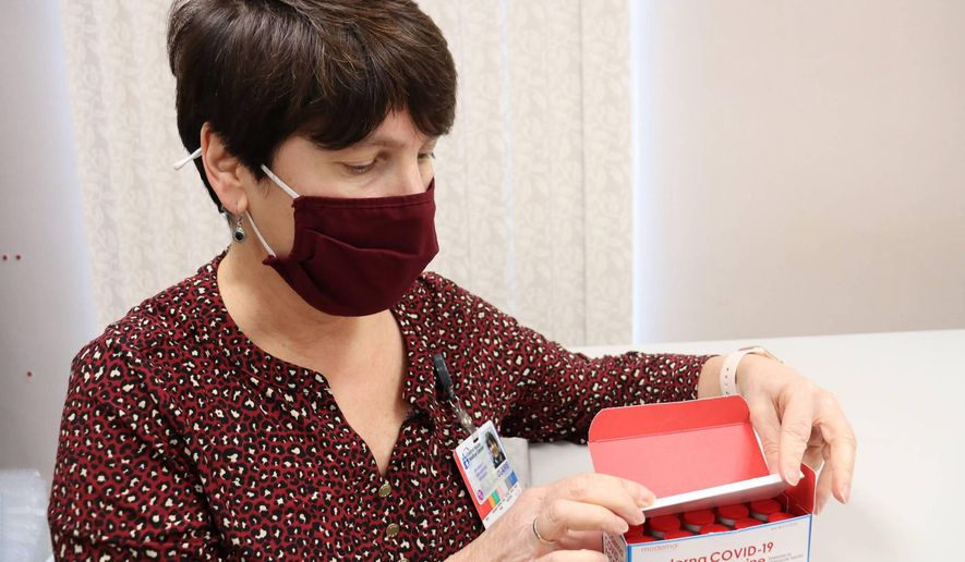 Claire McDonough, pharmacy operations manager at Central Maine Healthcare, opens a box of Moderna COVID-19 coronavirus vaccines in Lewiston, Maine on Monday, Dec. 21, 2020, after receiving 600 doses at the Central Maine Medical Center. (Ann Kim/Central Maine Medical Center via AP)