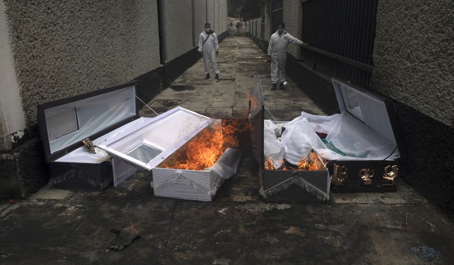 The coffins of COVID-19 victims burn after their bodies were cremated at the San Nicolas Tolentino cemetery in the Iztapalapa neighborhood of Mexico City, Wednesday, June 24, 2020. (AP Photo/Marco Ugarte)