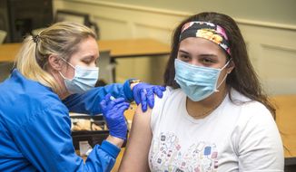 Registered nurse Betty Hallman, left, gives registered nurse Norma Elizondo a shot of the Pfizer COVID-19 vaccine at University Hospital in Augusta, Ga., Tuesday, Dec. 22, 2020. (Michael Holahan/The Augusta Chronicle via AP)