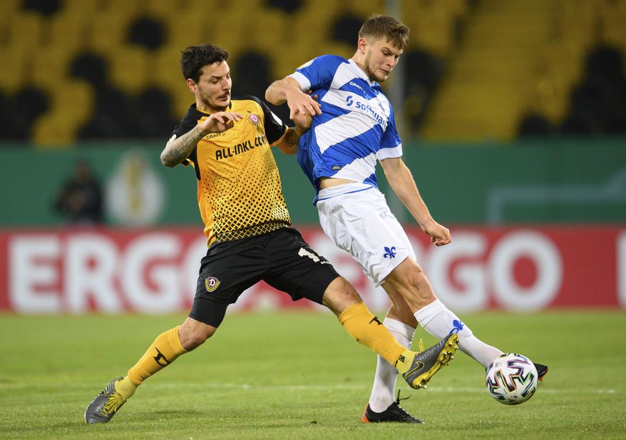 Dynamo's Philipp Hosiner, left, in action with Darmstadt's Lars Lukas Mai, during their German Bundesliga 2nd round soccer match at the Rudolf-Harbig-Stadion in Dresden, Germany, Tuesday Dec. 22, 2020. (Robert Michael/dpa via AP)
