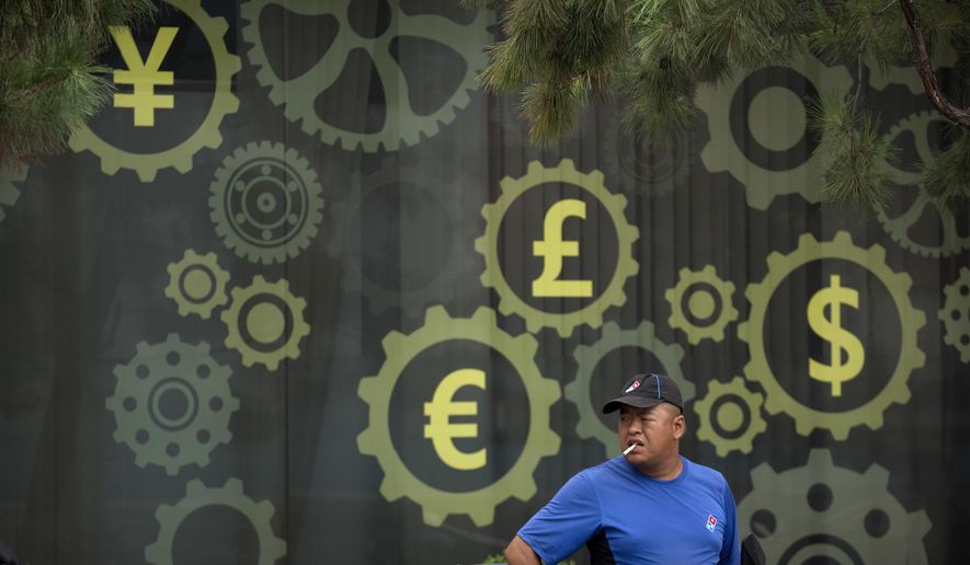 FILE - In this July 20, 2018, file photo, a deliveryman stands near a mural displaying Chinese yuan and other world currency symbols on the outside of a bank in Beijing. The official cost of the postponed Tokyo Olympics has increased by 22%, the local organizing committee said Tuesday, Dec. 22, 2020, in unveiling its new budget.(AP Photo/Mark Schiefelbein, File)