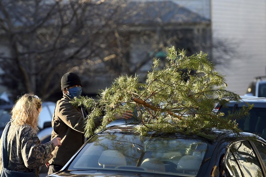 Parker Vivier and Marsden Olsen, both of Richmond, prepare to tie their tree to their car after purchasing from Frank Pichel's tree lot, Sunday, Dec. 6, 2020, in Richmond. (AP Photo/Will Newton)