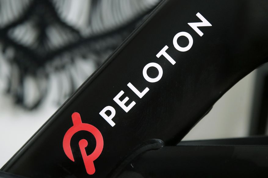 This Nov. 19, 2019, photo shows a Peloton logo on the company&#39;s stationary bicycle in San Francisco. Peloton is betting big that home workouts will continue to be popular next year and beyond, snapping up commercial exercise equipment maker Precor in a deal that will give Peloton its first manufacturing capacity in the U.S. Shares of Peloton jumped 13% in Tuesday, Dec. 21, 2020 trading, signaling investors like the move. (AP Photo/Jeff Chiu)