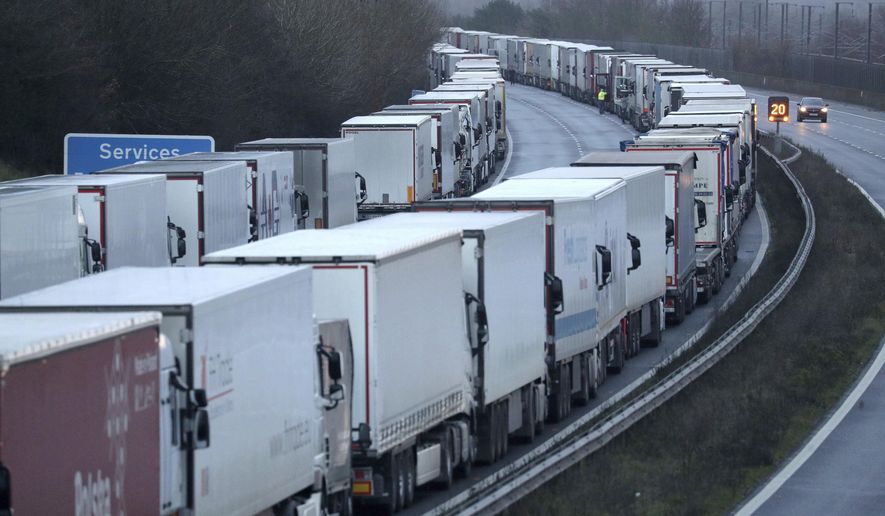 Trucks are parked along the M20 motorway where freight traffic is halted whilst the Port of Dover remains closed, in Ashford, Kent, England, Tuesday, Dec. 22, 2020. Trucks waiting to get out of Britain backed up for miles and people were left stranded at airports as dozens of countries around the world slapped tough travel restrictions on the U.K. because of a new and seemingly more contagious strain of the coronavirus in England. (Andrew Matthews/PA via AP)