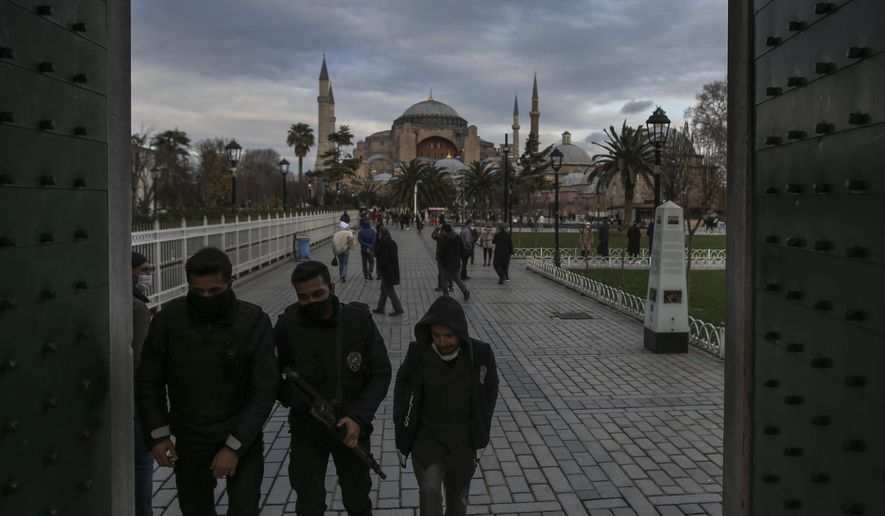 Police officers, wearing protective masks to help curb the spread of the coronavirus, backdropped by the Byzantine-era Hagia Sophia, patrol the historic Sultanahmet district of Istanbul, Monday, Dec. 21, 2020. Turkey has become one of the worst-hit countries in the world, with the number of confirmed cases hovering around 30,000 per day.The country has imposed evening curfews and lockdowns at weekends to try and combat the surge without impacting the economy but medical groups and opposition parties say the measures will fail to curb the spread. (AP Photo/Emrah Gurel)
