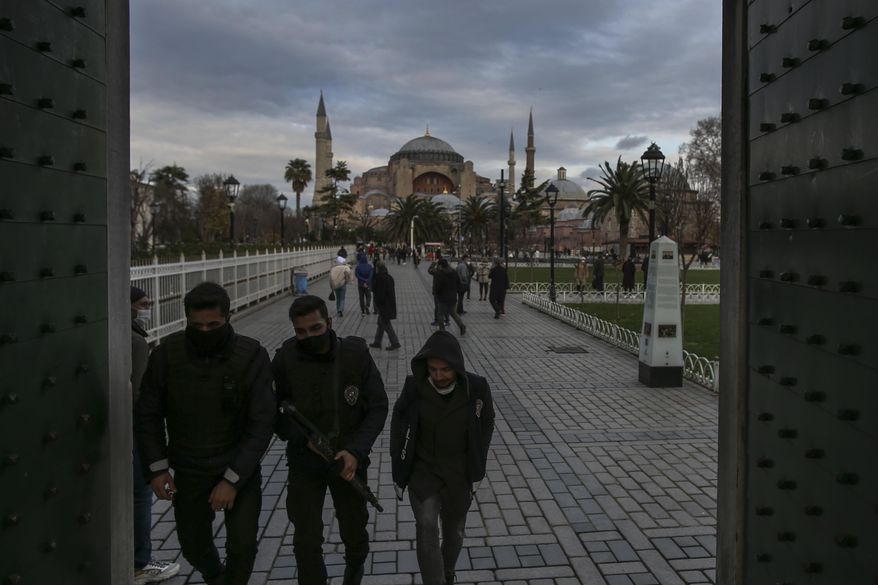 Police officers, wearing protective masks to help curb the spread of the coronavirus, backdropped by the Byzantine-era Hagia Sophia, patrol the historic Sultanahmet district of Istanbul, Monday, Dec. 21, 2020. Turkey has become one of the worst-hit countries in the world, with the number of confirmed cases hovering around 30,000 per day.The country has imposed evening curfews and lockdowns at weekends to try and combat the surge without impacting the economy but medical groups and opposition parties say the measures will fail to curb the spread. (AP Photo/Emrah Gurel)