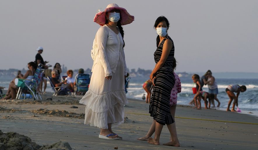 FILE - In this Aug. 11, 2020, file photo, women wear masks to help prevent the spread of coronavirus at the end of a beach day in Ogunquit, Maine. The virus, which killed more than 230 in Maine and crippled the state's economy, was voted unanimous top story of 2020 in Maine by The Associated Press. (AP Photo/Robert F. Bukaty, File)