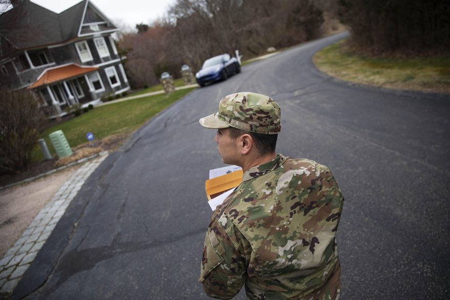 FILE - In this March 28, 2020, file photo, Rhode Island Air National Guard Tsgt. William Randall walks through the Watch Hill neighborhood looking for New York residents to inform them of self quarantine orders in Westerly, R.I. The coronavirus pandemic was Rhode Island's top story of 2020. (AP Photo/David Goldman, File)