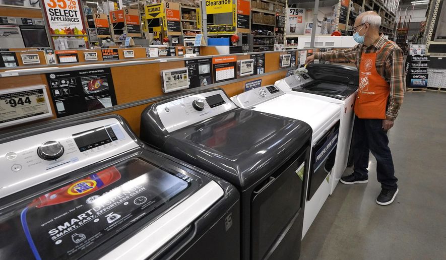 Worker Javad Memarzadeh, of Needham, Mass., right, dusts washers in a display, Thursday, Oct. 29, 2020, at a Home Depot location, in Boston. Orders to U.S. factories for big-ticketed manufactured goods rose a moderate 0.9% in November with a key category that tracks business investment plans showing a gain. The Commerce Department said Wednesday, Dec. 23 that the November gain in orders for durable goods, items expected to last at least three years, followed stronger gains in recent months including a 3.8% rise in October.(AP Photo/Steven Senne)