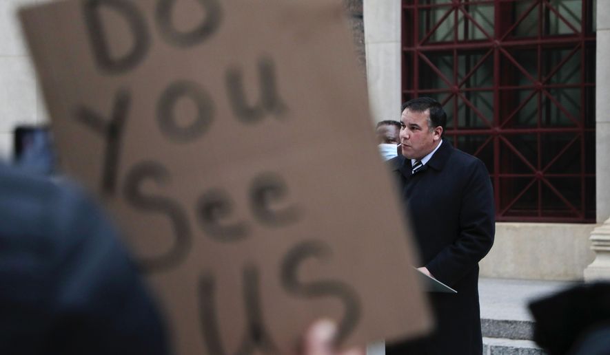 A demonstrator holds up a sign as Columbus Mayor Andrew J. Ginther speaks during a press conference following a fatal police shooting on Tuesday, Dec. 22, 2020 at City Hall in Columbus, Ohio. A police officer who shot and killed a Black man holding a cell phone in Ohio's capital city early Tuesday did not activate his body camera beforehand, and dash cameras on the officers' cruiser were also not activated, city officials said. (Joshua A. Bickel/The Columbus Dispatch via AP)
