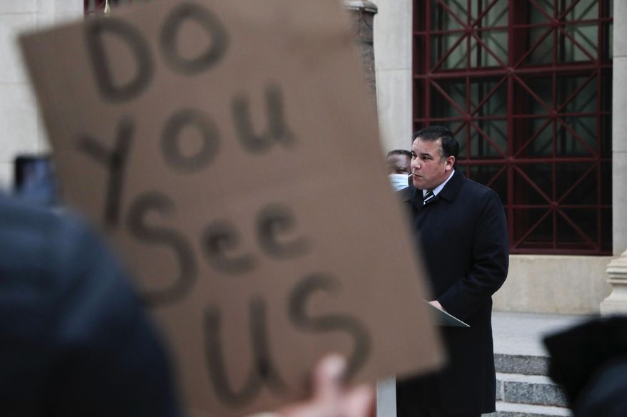 A demonstrator holds up a sign as Columbus Mayor Andrew J. Ginther speaks during a press conference following a fatal police shooting on Tuesday, Dec. 22, 2020 at City Hall in Columbus, Ohio. A police officer who shot and killed a Black man holding a cell phone in Ohio's capital city early Tuesday did not activate his body camera beforehand, and dash cameras on the officers' cruiser were also not activated, city officials said. (Joshua A. Bickel/The Columbus Dispatch via AP)