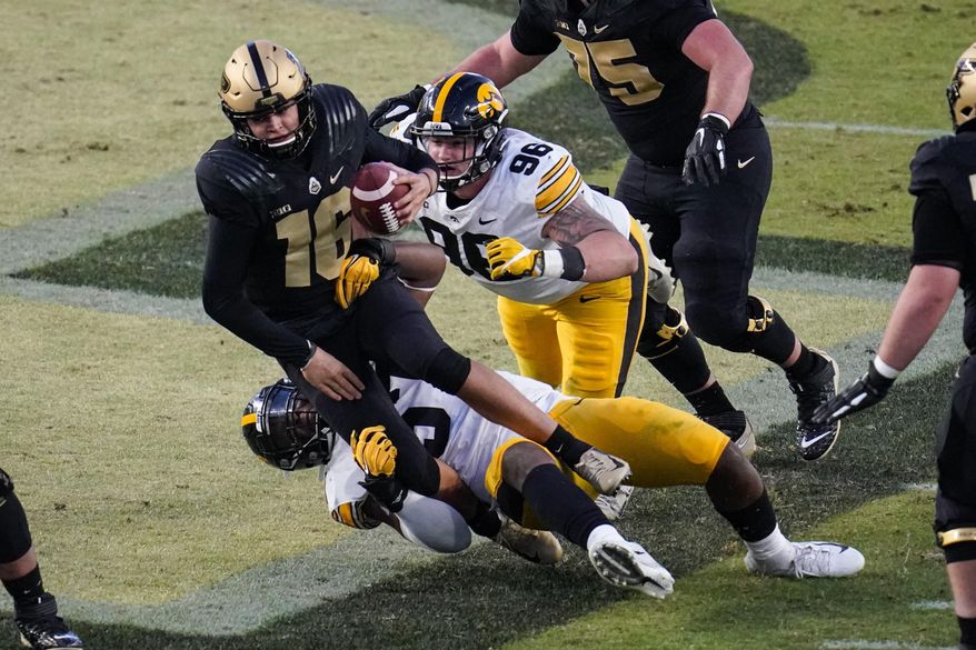 FILE - In this Oct. 24, 2020, file photo, Purdue quarterback Aidan O'Connell (16) is sacked by Iowa defensive linemen Jack Heflin (96) and Chauncey Golston (57) during the fourth quarter of an NCAA college football game in West Lafayette, Ind. Heflin is right where he always wanted to be. Heflin has turned his childhood aspirations into reality, suiting up this season for the No. 17 Hawkeyes after four years at Northern Illinois. The 22-year-old Heflin has 21 tackles and a sack playing a key role in anchoring one of the nation’s top defenses, which takes on Missouri in the Music City Bowl next week. (AP Photo/Michael Conroy, File)