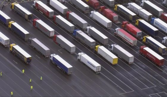 Trucks are parked in a holding area, in this aerial photo taken from video, lined up at former airfield in Manston, England, close to the M20 highway that runs to the port of Dover, Britain&#39;s main ferry connection with mainland Europe in northern France, Tuesday Dec. 22, 2020. The goods trucks are waiting to get out of Britain as France barred travel from the UK for 48 hours because of a new and seemingly more contagious strain of the coronavirus in England. (Sky via AP)