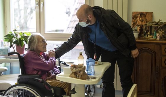 Marguerite Mouille, left, is greeted by her grandson Thierry Mouille at a nursing home in Kaysesberg, eastern France, Monday Dec. 21, 2020. Thierry Mouille is torturing himself over the government&#39;s Christmas offer of a three-week window of relaxed rules. He&#39;s changed his mind again and again about whether to bring his 94-year-old grandmother Marguerite out to share a holiday meal. (AP Photo/Jean-Francois Badias)