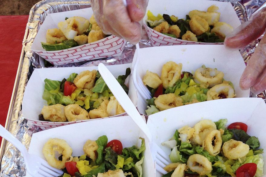 FILE - In this June 27, 2014, file photo, plates of fried calamari are served at the town dock in Narragansett, R.I., after Gov. Lincoln Chafee signed legislation to give the squid dish official status as Rhode Island's state appetizer. During the August 2020 televised virtual Democratic National Convention's roll call voting, the state's Democratic Party chair Joseph McNamara stood on a beach with a restaurateur holding a heaping plate of the squid and proclaimed Rhode Island the "calamari comeback state." (AP Photo/Jennifer McDermott, File)