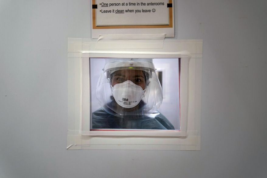 Registered nurse Nicole Grecco looks through a small window while working in a COVID-19 unit at Mission Hospital in Mission Viejo, Calif., Monday, Dec. 21, 2020. (AP Photo/Jae C. Hong)