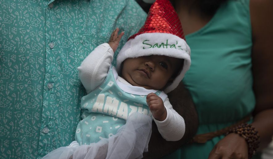 A baby is dressed in a Santa hat at a shopping mall in Johannesburg, South Africa, Tuesday, Dec. 22, 2020. (AP Photo/Denis Farrell) ** FILE **