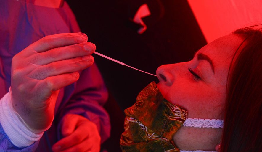 FILE - In this May 14, 2020, file photo, Jason Antos, left, an Advanced EMT for Rescue Inc., inserts a testing swab into the nasal passage of Anya Wolfe, of Wardsboro, Vt., during a pop-up coronavirus testing clinic at the Brattleboro Union High School&#x27;s parking lot, in Brattleboro, Vt. The coronavirus pandemic was Vermont&#x27;s top story of 2020. (Kristopher Radder/The Brattleboro Reformer via AP, File)