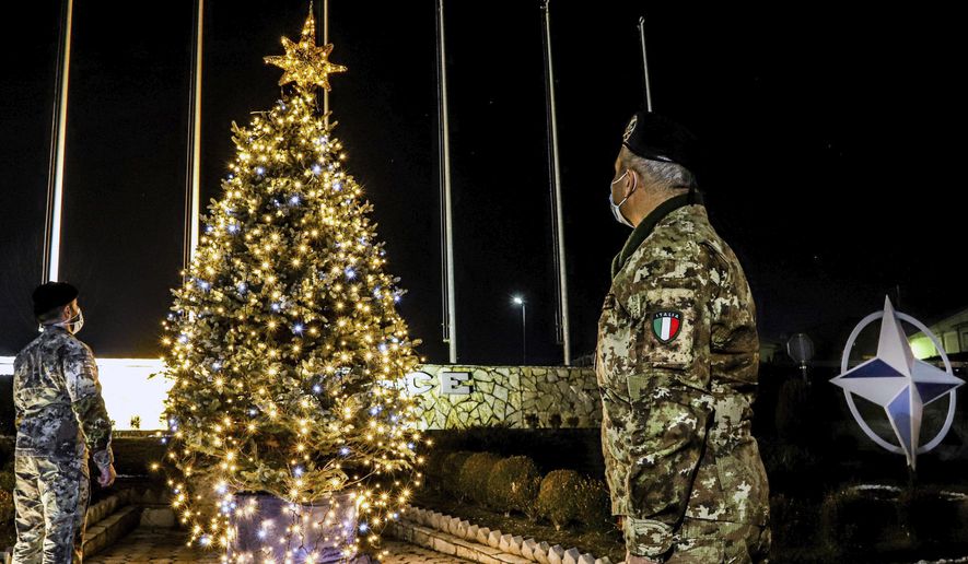 In this photo provided by NATO-led peacekeeping mission in Kosovo (KFOR), Italian soldiers watch Christmas tree on the Christmas Eve in the KFOR military headquarters in Kosovo capital Pristina, Thursday, Dec. 24, 2020. The coronavirus pandemic has totally changed Christmas time operation method and celebrations for the Kosovo Force but it has left unchanged its mission: keeping Kosovo safe and secure for 22 years now on. (KFOR via AP)