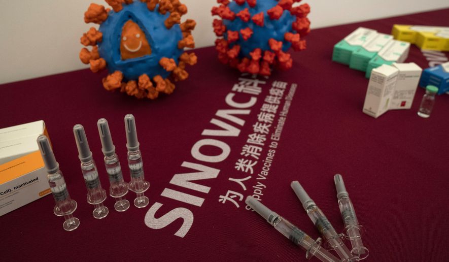 Syringes of a vaccine for COVID-19 and models depicting the coronavirus are displayed at the Sinovac factory in Beijing on Thursday, Sept. 24, 2020. With rich countries snapping up supplies of COVID-19 vaccines, some parts of the world may have to rely on Chinese-developed shots to conquer the outbreak. The question: Will they work? (AP Photo/Ng Han Guan) ** FILE **