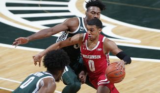 Wisconsin&#39;s D&#39;Mitrik Trice, right, drives against Michigan State&#39;s Julius Marble II during the first half of an NCAA college basketball game, Friday, Dec. 25, 2020, in East Lansing, Mich. (AP Photo/Al Goldis)