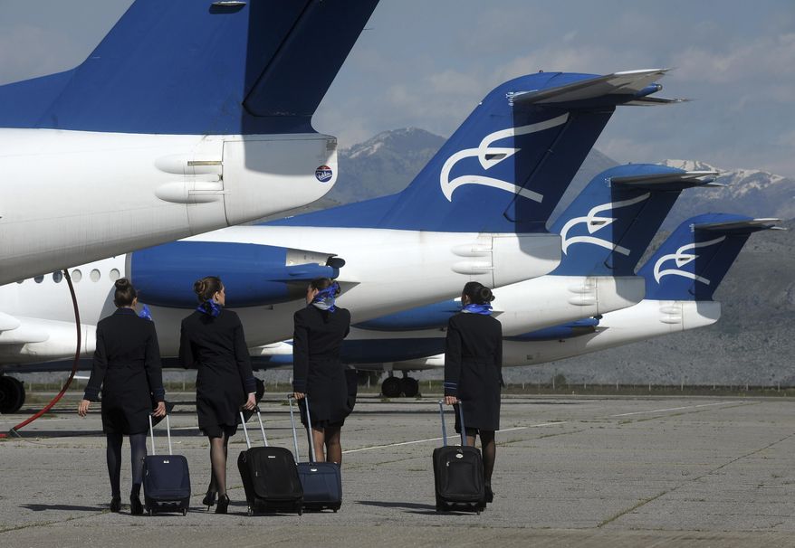 In this photo taken on April 10, 2014, Montenegro Airlines stewardesses walk to a plane on the tarmac at Golubovci airport, near Podgorica, Montenegro. Montenegro Airlines ceased its operations on Saturday, Dec. 26, 2020 after the small country's new government refused to continue financing the national carrier. The airline which was formed 25 years ago has apologized to its passengers for the sudden termination of all flights and thanked them for "the years of trust, travel and friendship." (AP Photo/Risto Bozovic)