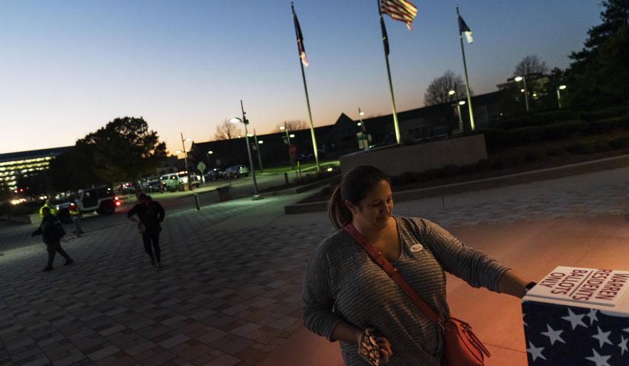 FILE - In this Tuesday, Nov. 3, 2020 file photo, Wendy Gill inserts her absentee ballot at a drop-off box as the sun sets on Election Day outside City Hall in Warren, Mich. The pandemic triggered wholesale changes to the way Americans voted in 2020, but that's no guarantee measures making it easier to cast ballots will stick around for future elections. (AP Photo/David Goldman)