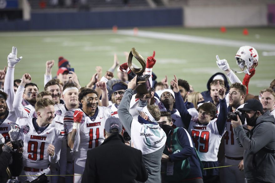 Liberty coach Hugh Freeze holds the trophy and celebrates with players after the team's overtime win over Coastal Carolina in the Cure Bowl NCAA college football game Saturday, Dec. 26, 2020, in Orlando, Fla. (AP Photo/Matt Stamey)