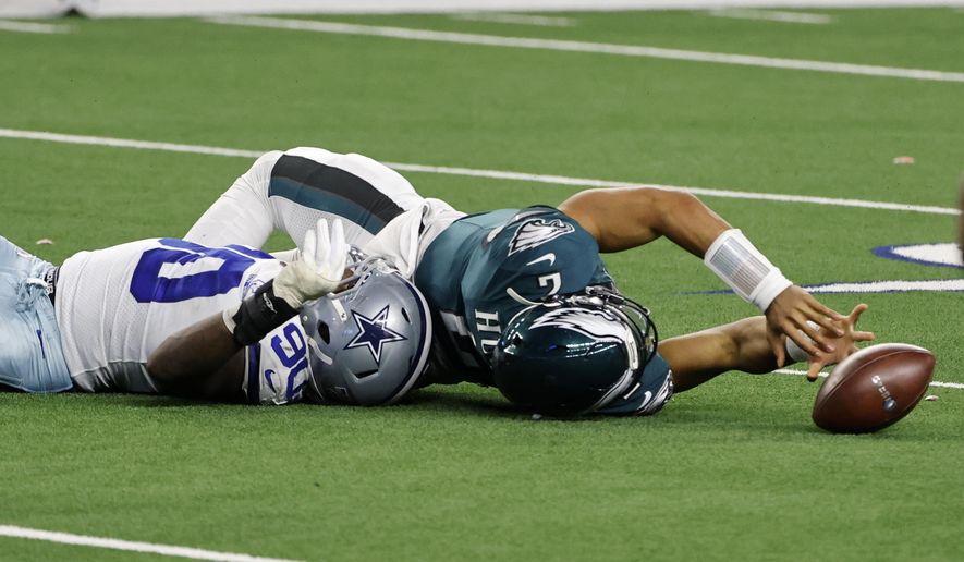 Dallas Cowboys defensive end DeMarcus Lawrence helps stop Philadelphia Eagles quarterback Jalen Hurts (2), who fumbled the ball on a run in the second half of an NFL football game in Arlington, Texas, Sunday, Dec. 27. 2020. The Cowboys recovered the fumble. (AP Photo/Michael Ainsworth)