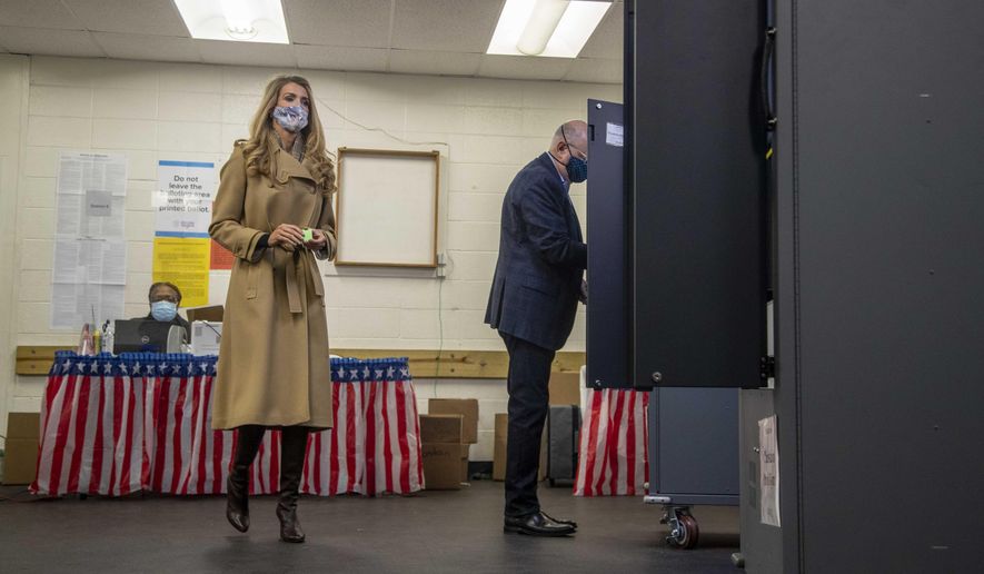 U.S. Sen. Kelly Loeffler, R-Ga., prepares to cast her ballot alongside her husband, Jeff Sprecher, right, during early voting in runoff elections at Chastain Park Gymnasium in Atlanta's Chastain Park neighborhood, Wednesday, Dec. 16, 2020. (Alyssa Pointer/Atlanta Journal-Constitution via AP) **FILE**