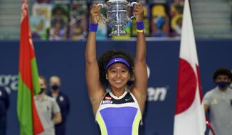 In this Sept. 12, 2020, file photo, Naomi Osaka, of Japan, holds up the championship trophy after defeating Victoria Azarenka, of Belarus, in the women&#39;s singles final of the U.S. Open tennis tournament in New York.  Osaka has been selected by The Associated Press as the Female Athlete of the Year.(AP Photo/Seth Wenig) **FILE**