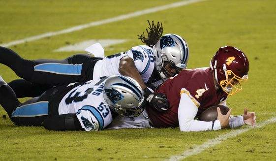 Washington Football Team quarterback Taylor Heinicke (4) is tackled by Carolina Panthers defensive end Brian Burns (53) and linebacker Julian Stanford (50) near the end of an NFL football game, Sunday, Dec. 27, 2020, in Landover, Md. Carolina won 20-13 (AP Photo/Mark Tenally)
