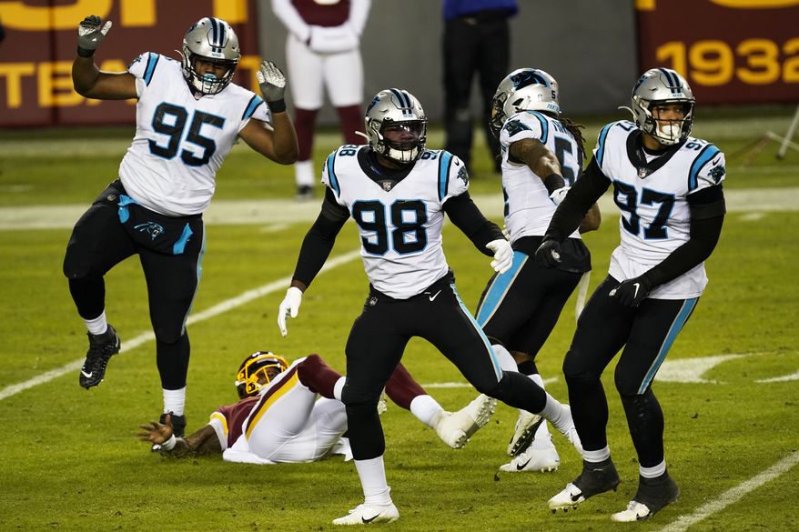 Carolina Panthers defense knocks Washington Football Team quarterback Dwayne Haskins (center) to the ground during an NFL football game between the Carolina Panthers and the Washington Football Team, Sunday, Dec. 27, 2020, in Landover, Md. (AP Photo/Mark Tenally)