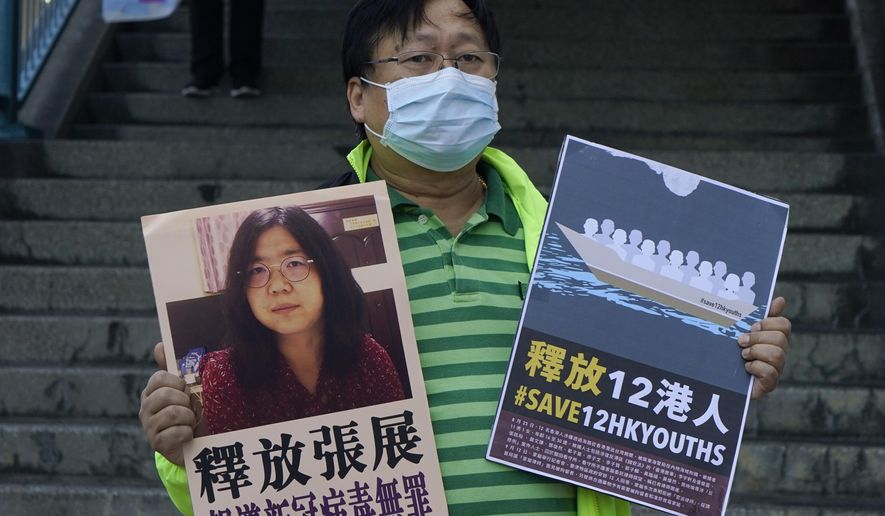 A pro-democracy activist holds placards with the picture of Chinese citizen journalist Zhang Zhan outside the Chinese central government's liaison office, in Hong Kong, Monday, Dec. 28, 2020. Zhang, a former lawyer and citizen journalist from Shanghai, has been sentenced to four years in prison for her reporting on the initial coronavirus outbreak in Wuhan, China. The activists demand the releases of Zhang, as well as the 12 Hong Kong activists detained at sea by Chinese authorities. (AP Photo/Kin Cheung)
