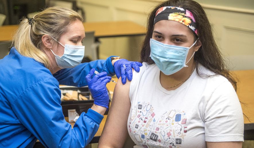 Registered nurse Betty Hallman, left, gives registered nurse Norma Elizondo a shot of the Pfizer COVID-19 vaccine at University Hospital in Augusta, Ga., Tuesday, Dec. 22, 2020. (Michael Holahan/The Augusta Chronicle via AP)