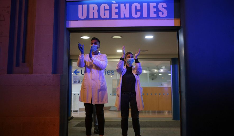FILE - In this March 16, 2020 file photo, health workers react as people applaud from their houses in support of the medical staff that are working in COVID-19 outbreak in Barcelona, Spain. Spain is restoring border controls and severely restricting who can enter the country. (AP Photo/Joan Mateu, File)