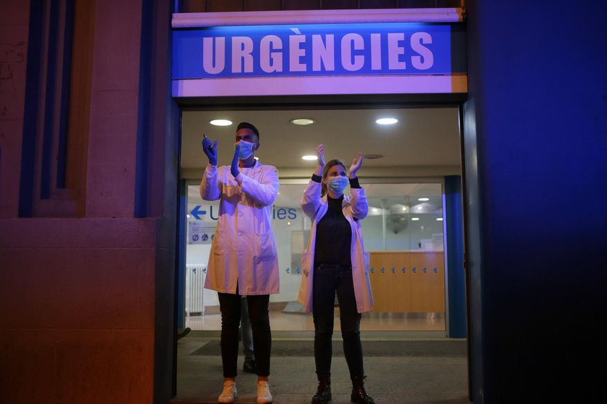 FILE - In this March 16, 2020 file photo, health workers react as people applaud from their houses in support of the medical staff that are working in COVID-19 outbreak in Barcelona, Spain. Spain is restoring border controls and severely restricting who can enter the country. (AP Photo/Joan Mateu, File)