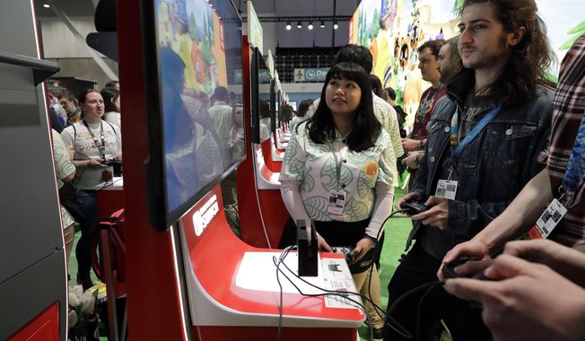 FILE - Visitors to the Pax East conference play the new Nintendo Switch video game Animal Crossing, Thursday, Feb. 27, 2020, in Boston. Thousands of gaming enthusiasts attended the Pax East conference that opened in Boston, Thursday. (AP Photo/Steven Senne)