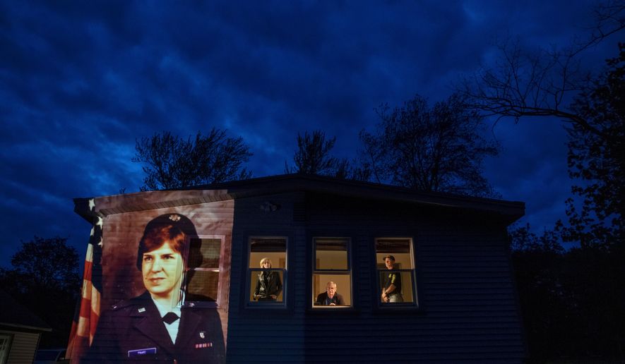 FILE - In this May 14, 2020, file photo, an image of veteran Constance &amp;quot;Kandy&amp;quot; Pinard is projected onto the home she grew up in with her sister, Tammy Petrowicz, left, and brothers, Paul, center, and Brian Driscoll in Florence, Mass. Pinard, a nurse in the U.S. Air Force and resident of the Soldier&#x27;s Home in Holyoke, Mass., died from the COVID-19 virus at the age of 73. The coronavirus pandemic was Massachusetts&#x27; top story of 2020. (AP Photo/David Goldman, File)