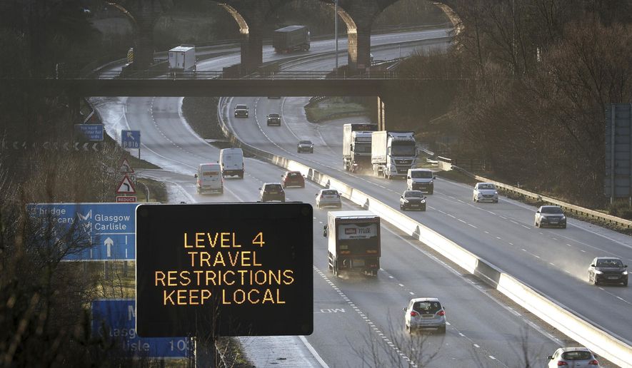 In this file photo, a traffic information board advises drivers to keep their travel to local trips because of coronavirus Level 4 restrictions, as traffic moves along the M80 motorway near Banknock, Scotland, Tuesday Dec. 29, 2020. Scotland has imposed more severe COVID-19 lockdown restrictions for several weeks. (Andrew Milligan/PA via AP) **FILE**