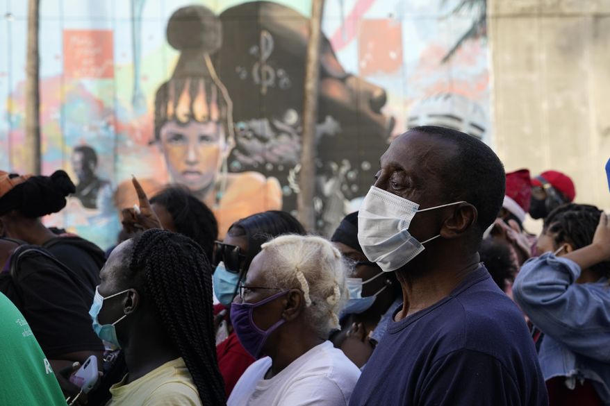Residents in the Overtown neighborhood of Miami wait in line to receive gift cards and gift bags with essentials, Tuesday, Dec. 29, 2020. Various organizations came together to distribute items to those in need during the coronavirus pandemic. Rapper Sean "Diddy" Combs also passed out fifty dollar bills to residents. (AP Photo/Lynne Sladky)