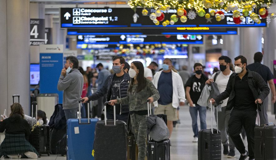 Travelers wearing protective face masks walk through Concourse D at Miami International Airport, Monday, Dec. 28, 2020, in Miami. (David Santiago/Miami Herald via AP) ** FILE **