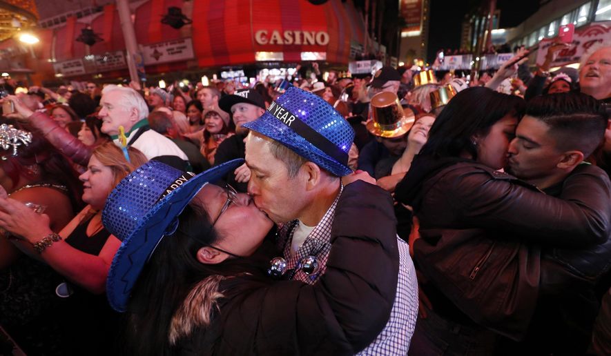 FILE - In this Jan. 1, 2018, file photo, newlyweds Alison and Kenny Finchum, lower left, of Tulsa, Okla., kiss just after midnight during a New Year&#39;s party at the Fremont Street Experience in downtown Las Vegas. Plans for a 14,000-person New Year&#39;s Eve street party at canopied casino-mall in Las Vegas are facing pushback from state and local officials, who worry Nevada hospitals may not be able to withstand a potential &amp;quot;superspreader&amp;quot; event. (Steve Marcus/Las Vegas Sun via AP, File)