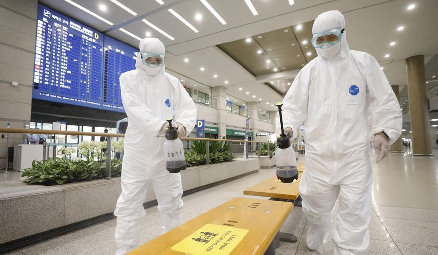 Workers wearing protective gears disinfect chairs as a precaution against the coronavirus at the arrival hall of the Incheon International Airport in Incheon, South Korea, Tuesday, Dec. 29, 2020. South Korea says 40 more coronavirus patients have died in the past 24 hours, the highest daily fatalities since the pandemic began, as the country is grappling with surging cases in recent weeks. (Ko Seung-min/Newsis via AP)