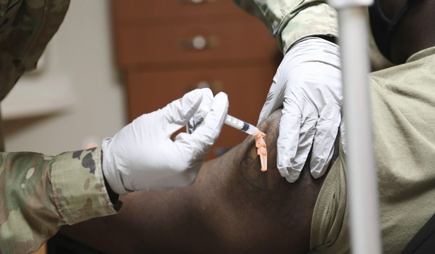 In this photo provided by United States Forces Korea, Sgt. Parmer Smith, 129 medical detachment, administers one of the first COVID-19 vaccines to Navy Petty Officer 2nd Class John London, a Hospital Corpsman, SOCKOR Medics, at Brian D. Allgood Army Community Hospital at U.S. Army Garrison Humphreys, in Pyeongtaek, South Korea Tuesday, Dec. 29, 2020.  The United States has started vaccinating its troops based in South Korea, as its Asian ally reported its highest daily COVID-19 fatalities amid surging cases in the country. (Spc. Erin Conway/United States Forces Korea vis AP)