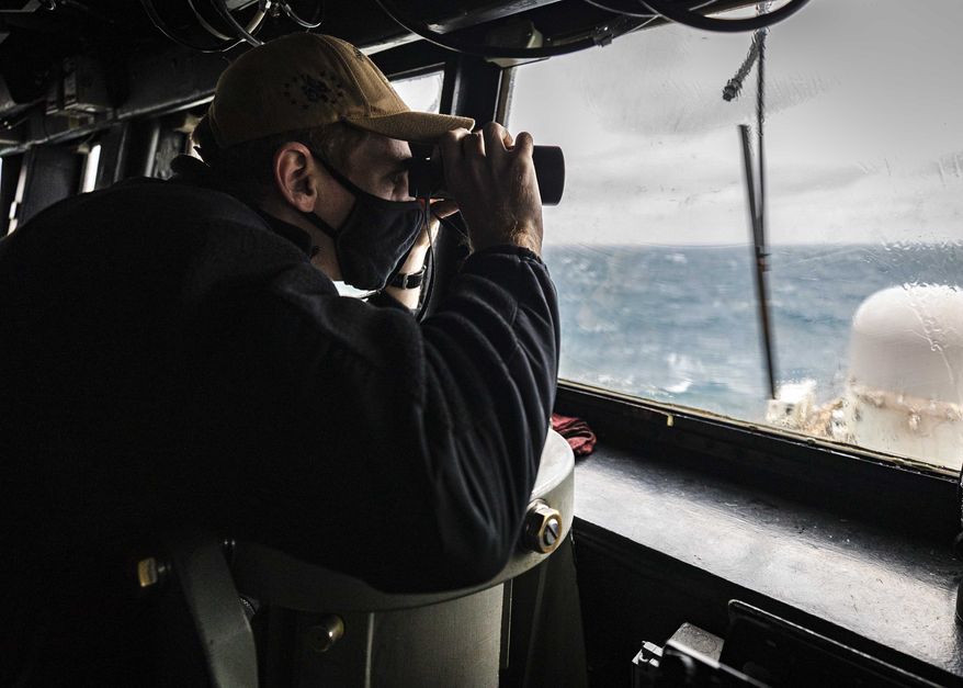 In this file photo provided by U.S. Navy, Ensign Grayson Sigler, from Corpus Christi, TX., scans the horizon while standing watch in the pilot house as guided-missile destroyer USS John S. McCain conducts routine underway operations in support of stability and security for a free and open Indo-Pacific, at the Taiwan Strait, Wednesday, Dec. 30, 2020. China accused the U.S. of staging a show of force by sailing two Navy warships through the Taiwan Strait on Thursday morning. The Navy said the Arleigh Burke-class guided missile destroyers USS John S. McCain and USS Curtis Wilbur conducted a routine Taiwan Strait transit in accordance with international law. (Mass Communication Specialist 2nd Class Markus Castaneda/U.S. Navy via AP)  **FILE**