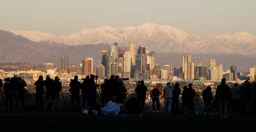 Photographers set their equipment as they are waiting to photograph the moon rising over snow covered mountains, behind the downtown Los Angeles skyline at Kenneth Hahn State Recreation Area Tuesday, Dec. 29, 2020, in Los Angeles. (AP Photo/Ringo H.W. Chiu)